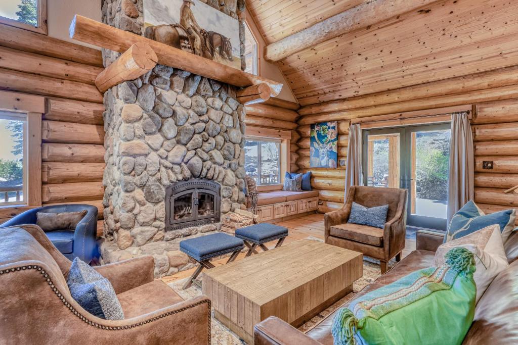 Cabaña de madera con sala de estar con chimenea de piedra. en Log Cabin Estate - Falcon Ridge, en Truckee