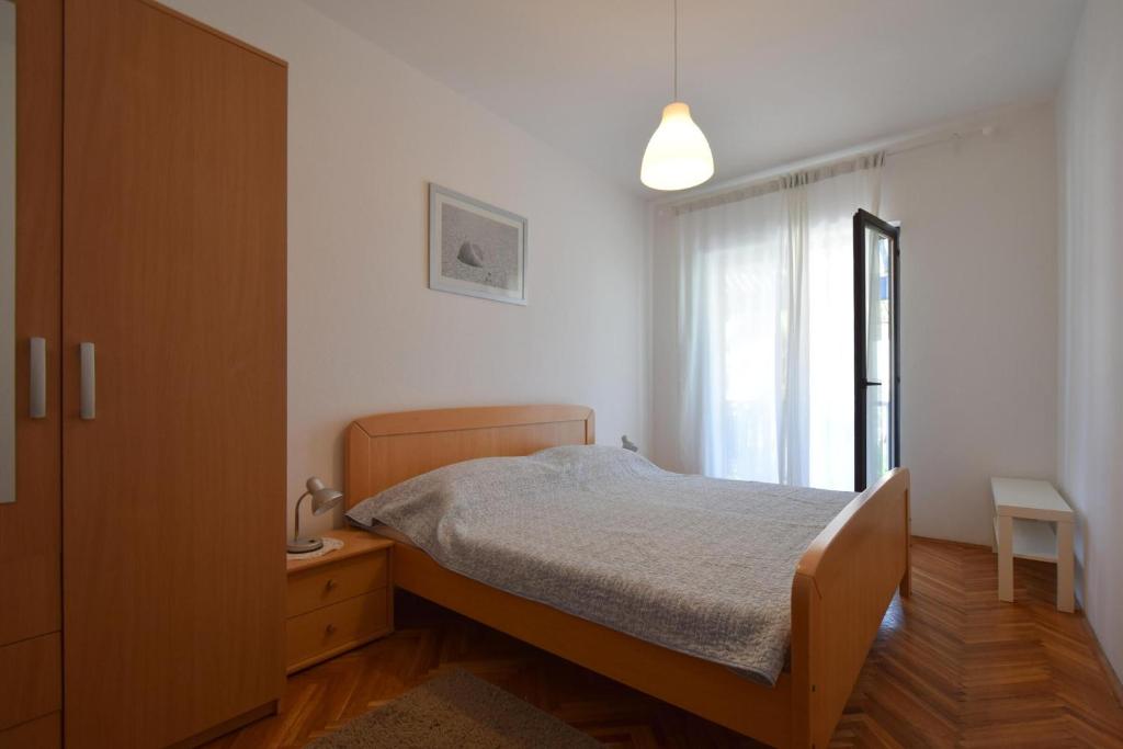 a bedroom with a bed and a dresser and a window at Apartment Lorela in Malinska