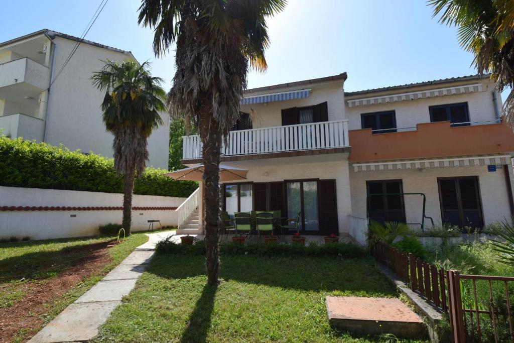 a house with palm trees in front of it at Apartment Lorela in Malinska