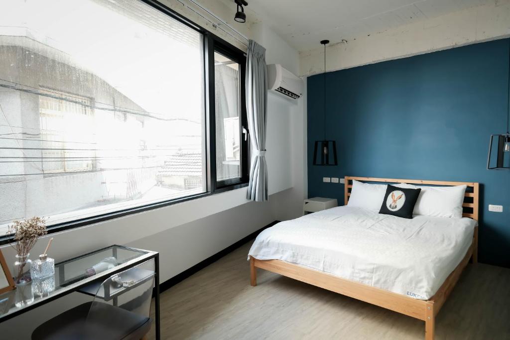 a bedroom with a blue accent wall and a bed at Luke 27 Homestay in Tainan