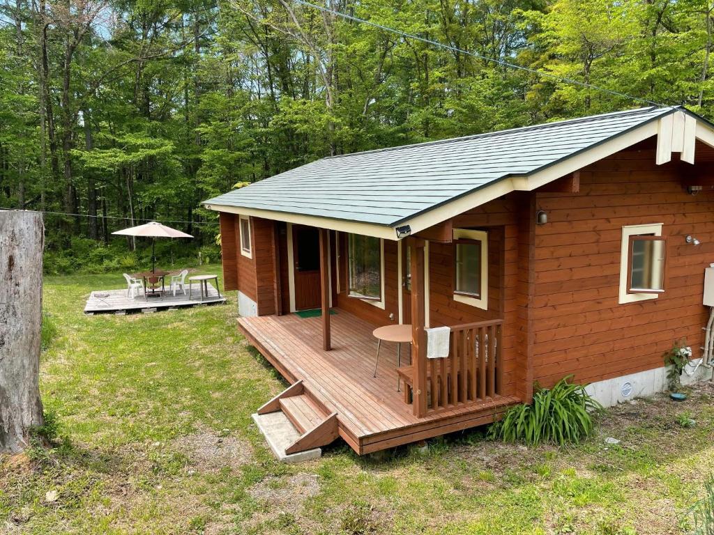 eine kleine Holzhütte mit einer Terrasse und einem Tisch in der Unterkunft Haramura CAFE Lodge - Vacation STAY 33104v in Hara