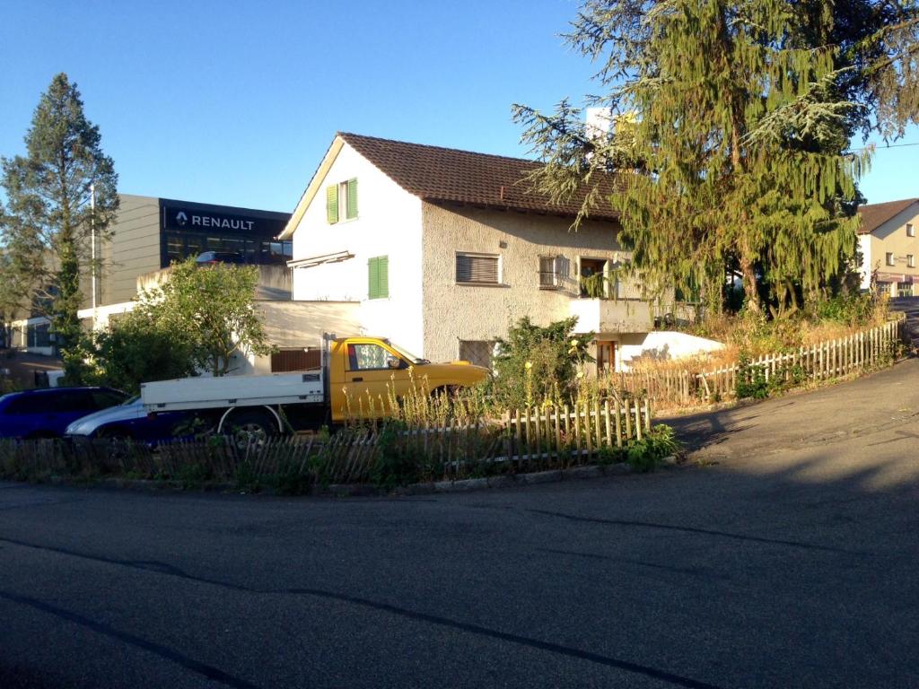 een gele truck geparkeerd voor een huis bij BaselHostel in Füllinsdorf