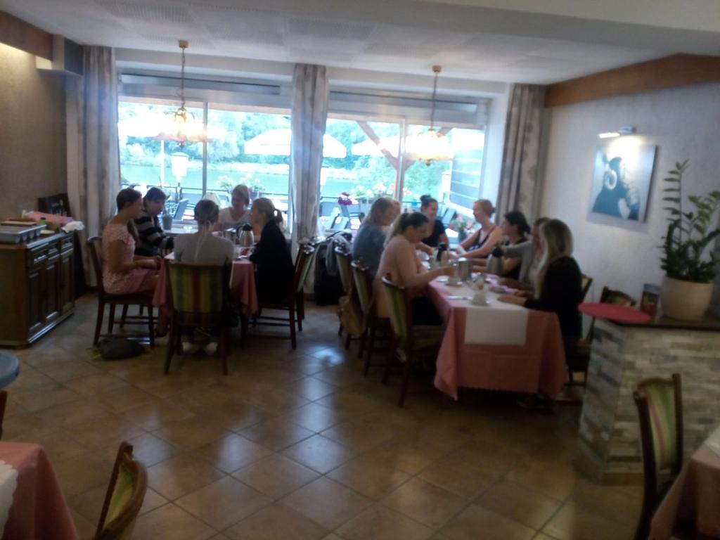 a group of people sitting at tables in a restaurant at Cafe Moselterrasse in Klotten