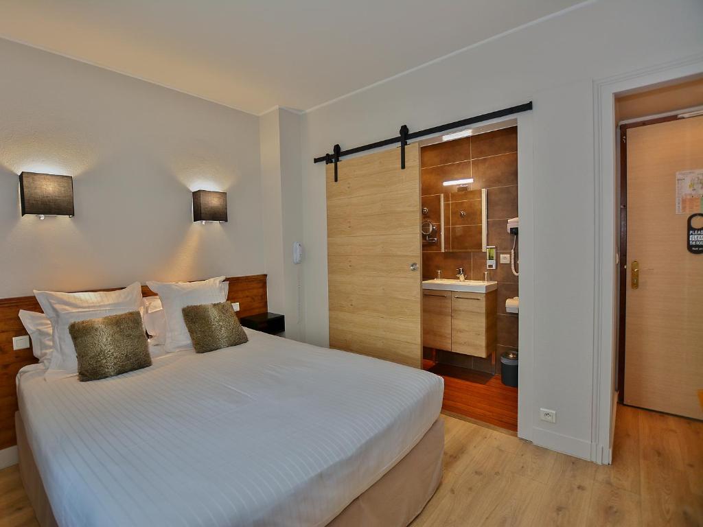A bed or beds in a room at Logis Hotel La Closerie