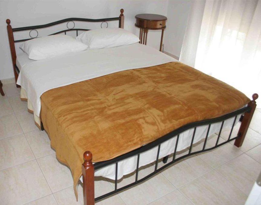 Schlafzimmer mit einem Bett mit einem Holzrahmen und weißer Bettwäsche in der Unterkunft To Portego tis Anatolis in Néa Péramos