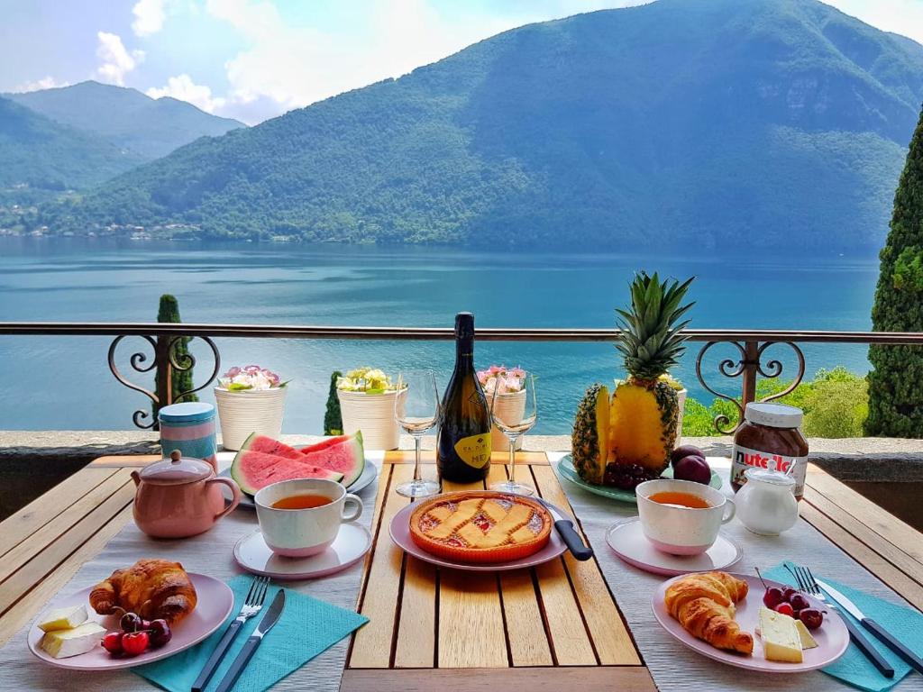 una mesa con comida y vistas al agua en Fabulous view on the Lake, en Valsolda
