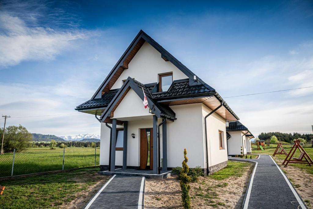 a small white house with a black roof at Prowincja Tatra Cottages in Dębno