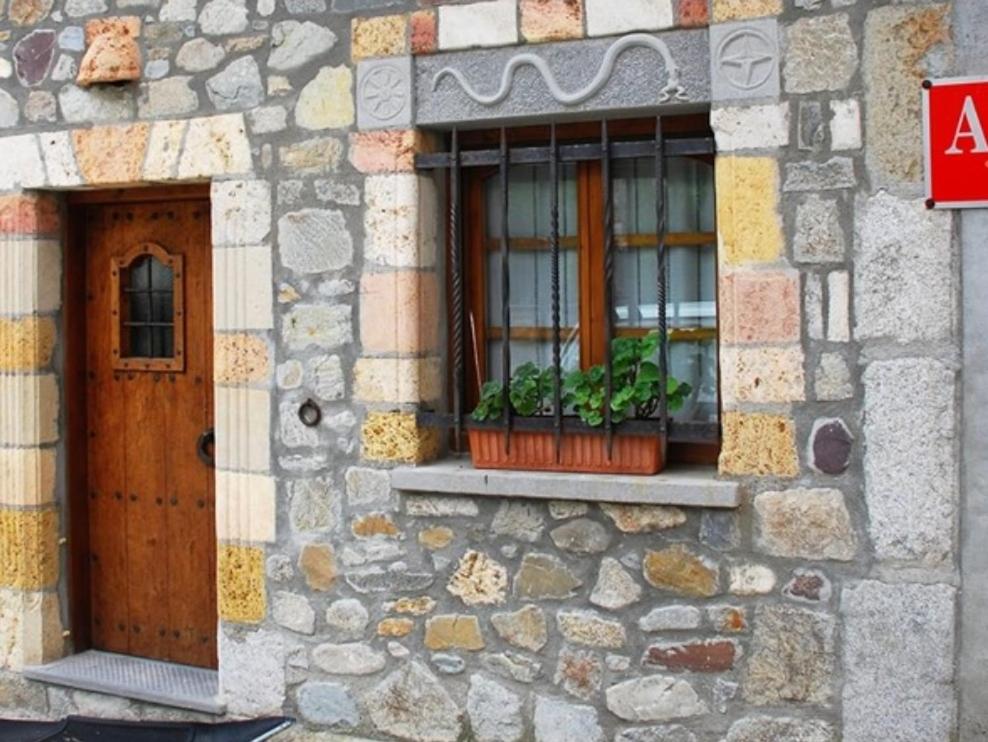 Caseta Sorripas في بييلسا: مبنى حجري مع نافذة تحتوي على اثنين من النباتات الفخارية