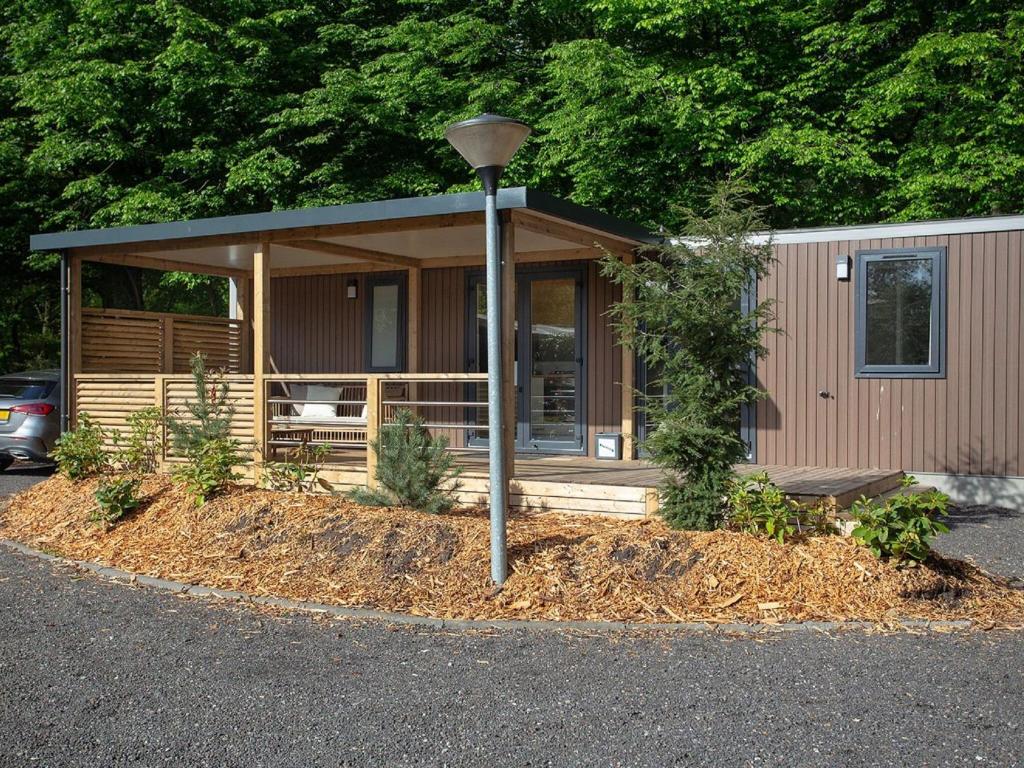 een kleine hut met een veranda en een straatlicht bij Attractive chalet with microwave and close to the forest in Rhenen