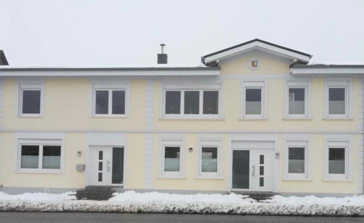 a large white house with snow in front of it at Ferienwohnung Maximilian in Grömitz