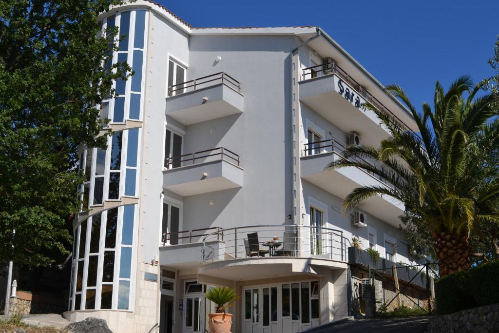 un edificio bianco con balconi e una palma di Sunčana Sara a Tučepi