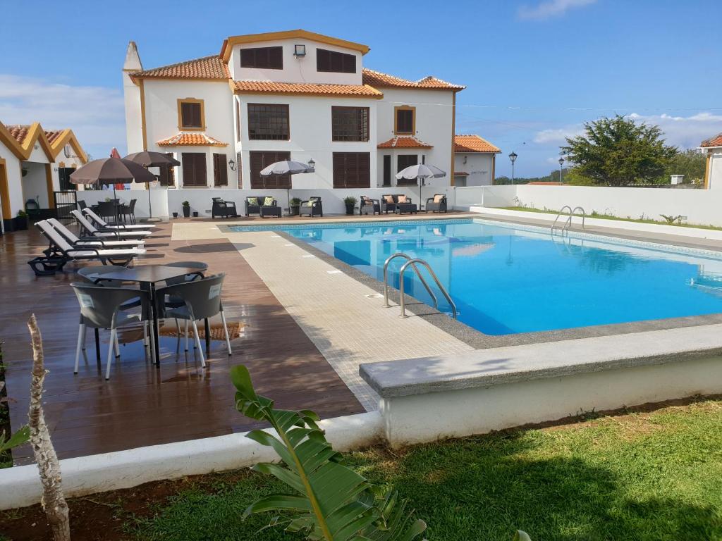 a swimming pool with a table and chairs next to a house at CASA MARQUES in Angra do Heroísmo