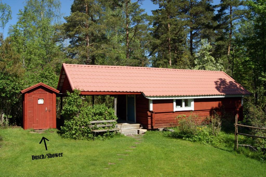 a red cabin with a red roof in the grass at Karlsäter - Stora stugan in Älvkarleby