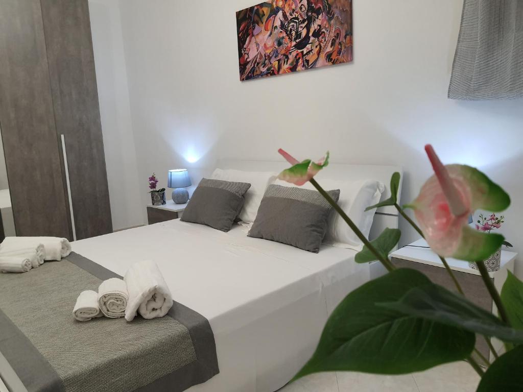 Appartamento Mattia في مارسالا: غرفة نوم بسرير ابيض ونبات