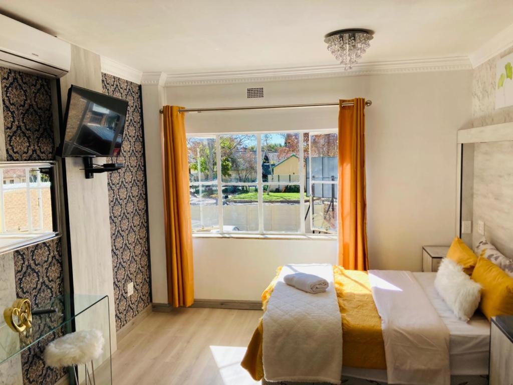 a bedroom with a bed and a large window at Abecor Hotel in Welkom