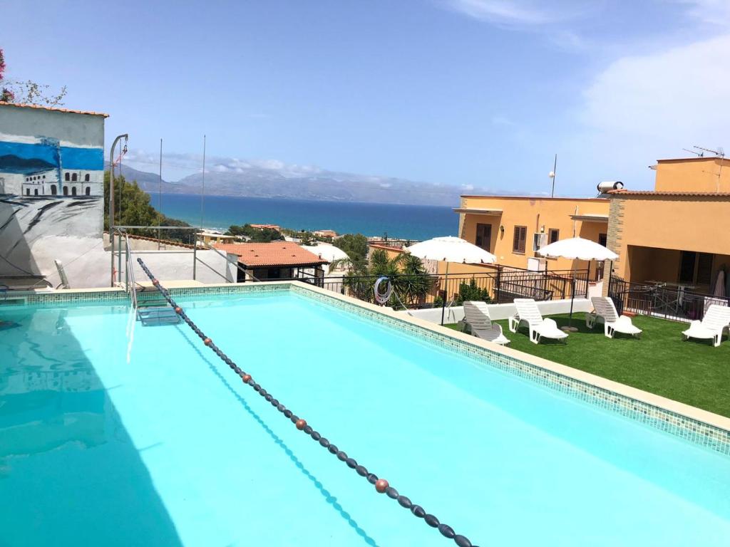 a swimming pool with chairs and a view of the water at case vacanze piccolo in Balestrate