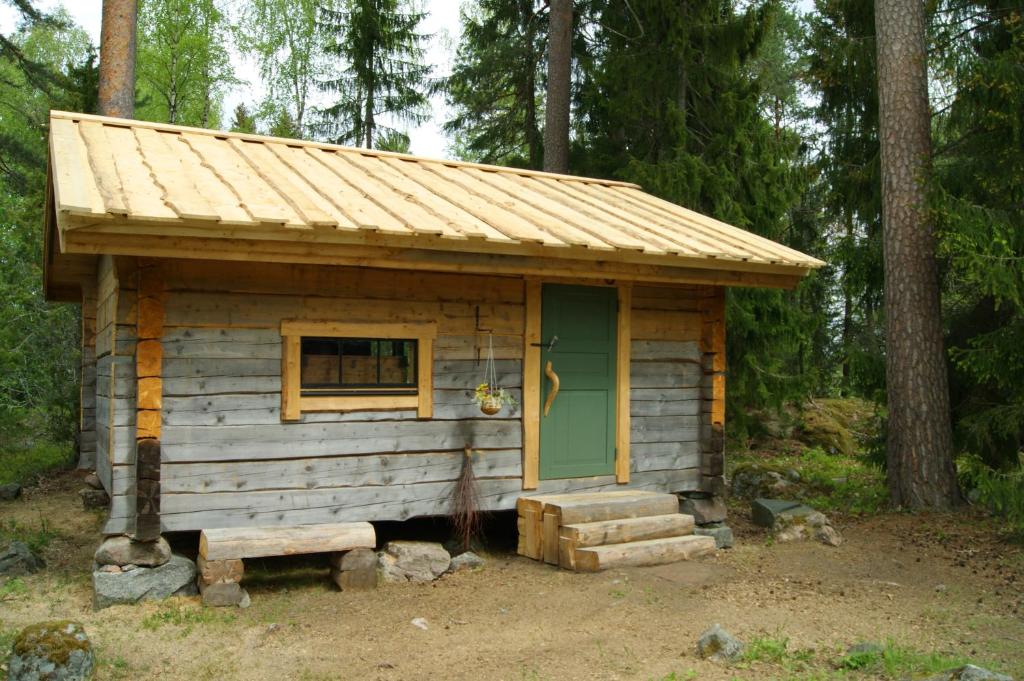 a small cabin with a green door in the woods at Karlsäter - Timmerstugan in Älvkarleby