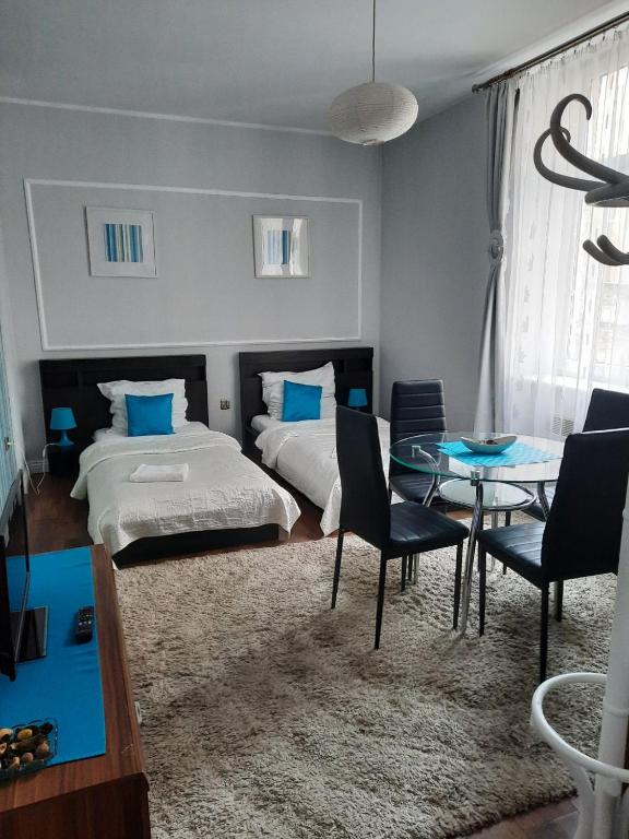 a bedroom with two beds and a table and chairs at Sleep Well in Poznań