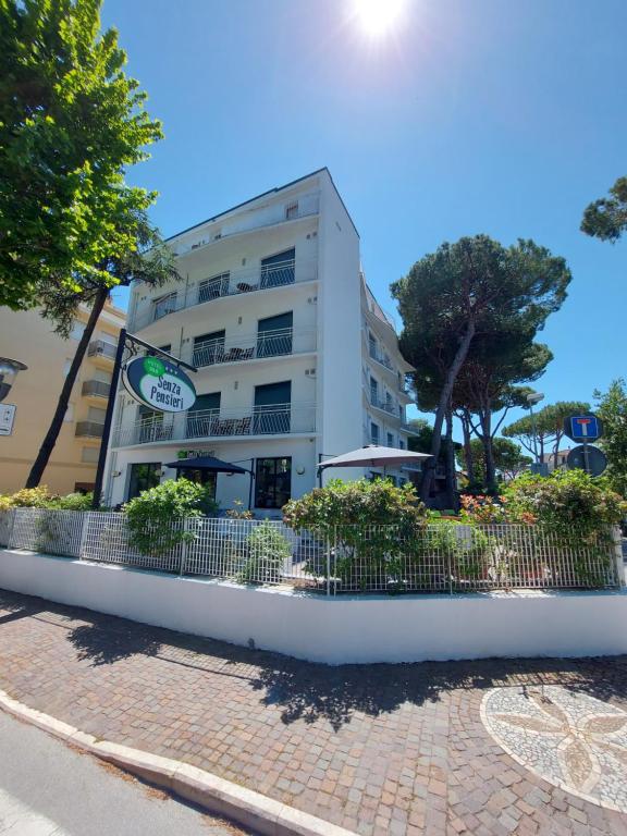 a white building with a fence in front of it at Hotel Senza Pensieri Riccione in Riccione
