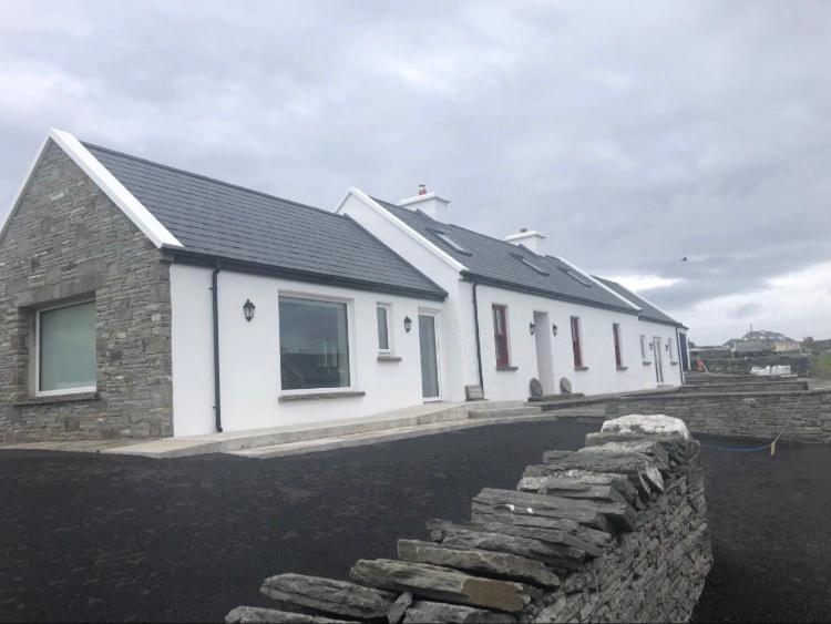 una casa blanca con una pared de piedra delante de ella en Conway's Cottage with Sea View Nestling by Cliffs-of-Moher, en Liscannor