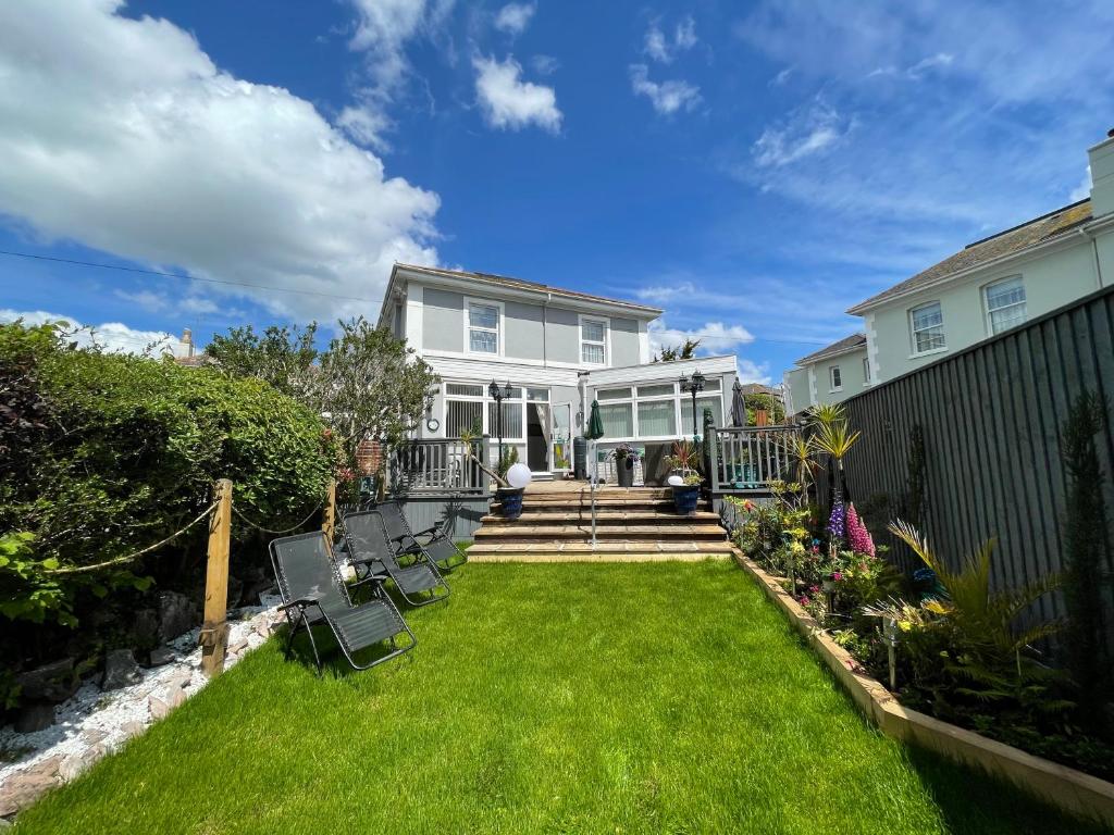 una casa blanca con un patio con césped verde en The Southbourne Villa, en Torquay