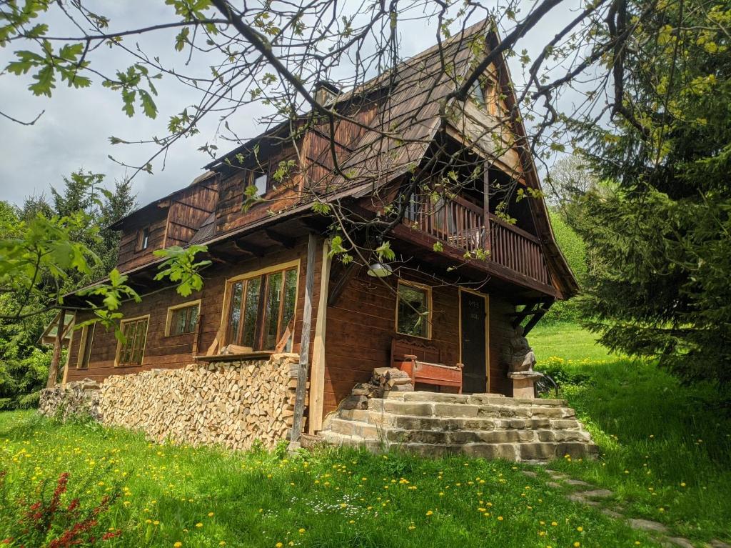 a log house with a porch and stairs in a field at Pokoje u Agnieszki in Dwernik