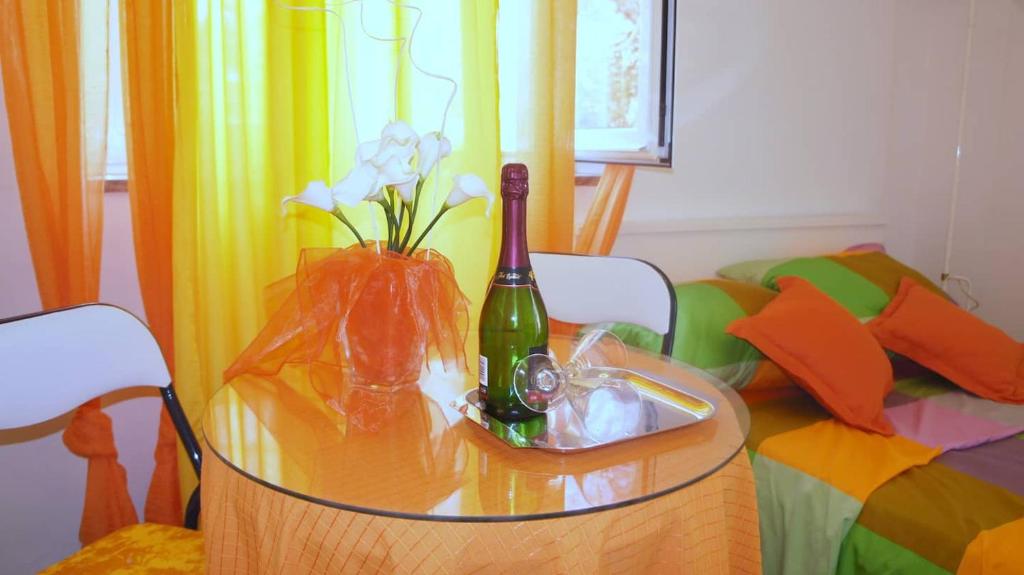 a glass table with a bottle of wine and flowers on it at Iva new room with private bathroom in Zadar