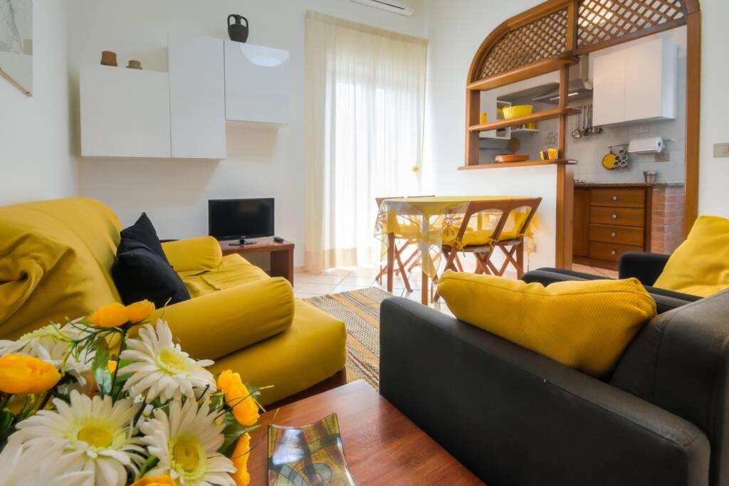 un soggiorno con divano giallo e tavolo di Sunset Alghero ad Alghero