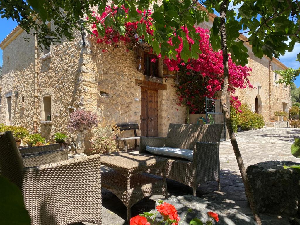 eine Terrasse mit Stühlen und einem Tisch sowie ein Gebäude mit Blumen in der Unterkunft Agroturismo Can Guillo in Pollença