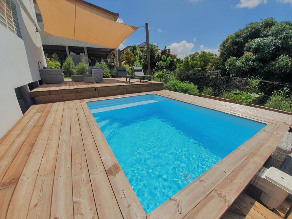 een zwembad met een houten terras naast een huis bij Kozycoco - Suite Kozy - séjour tropical au calme in Schœlcher