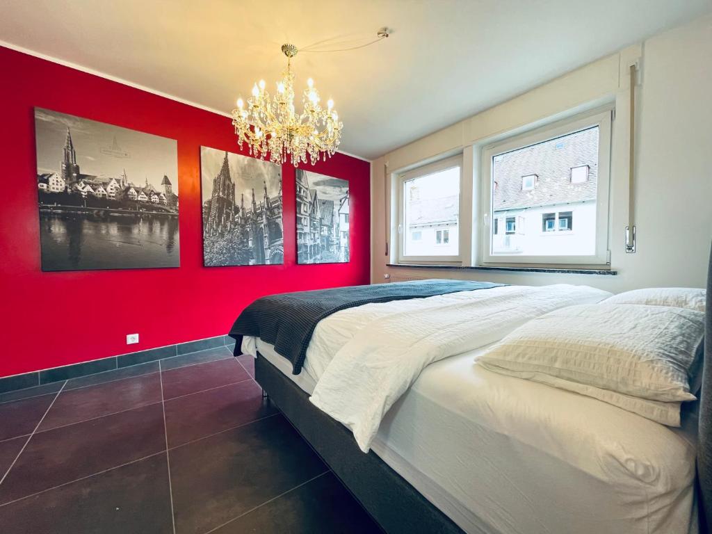 a red bedroom with a large bed and a chandelier at apartment11 in Ulm