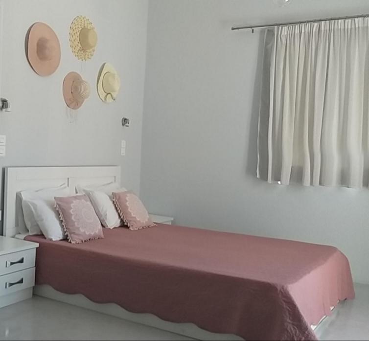 1 cama con almohadas rosas y blancas y ventana en Passos Rooms en Parikia