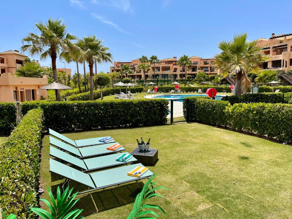 a yard with a blue bench and a swimming pool at Casares Beach Golf Apartment With Private Garden Direct Pool Access in Casares