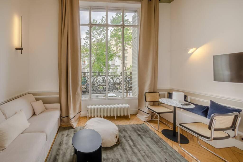 ein Wohnzimmer mit einem weißen Sofa und einem Fenster in der Unterkunft Appartement de standing 3 - tour Eiffel/Invalides in Paris