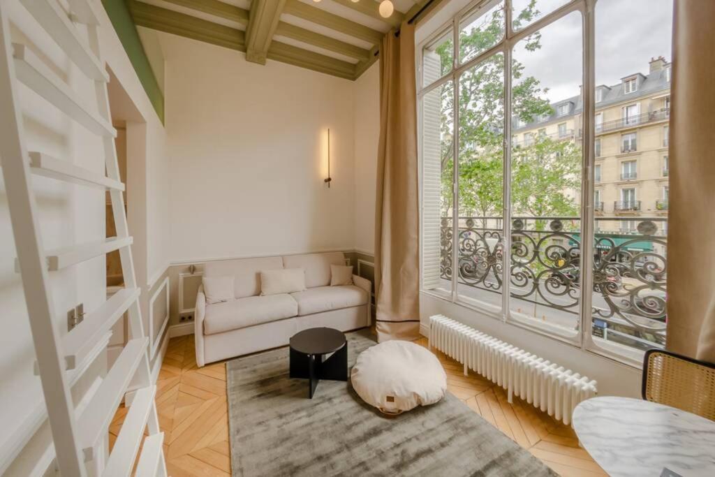 un salon avec un canapé et une grande fenêtre dans l'établissement Appartement de standing 3 - tour Eiffel/Invalides, à Paris