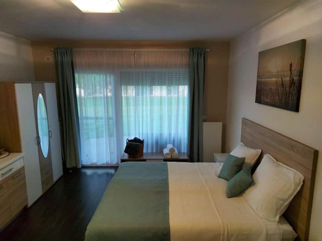 1 dormitorio con 1 cama grande con almohadas verdes en Bike & Spa Velence Apartman en Velence