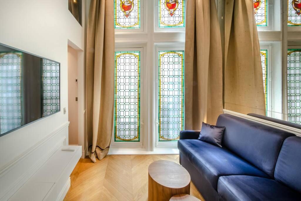 ein Wohnzimmer mit einem blauen Sofa und Buntglasfenstern in der Unterkunft Appartement de standing 5 - tour Eiffel/Invalides in Paris