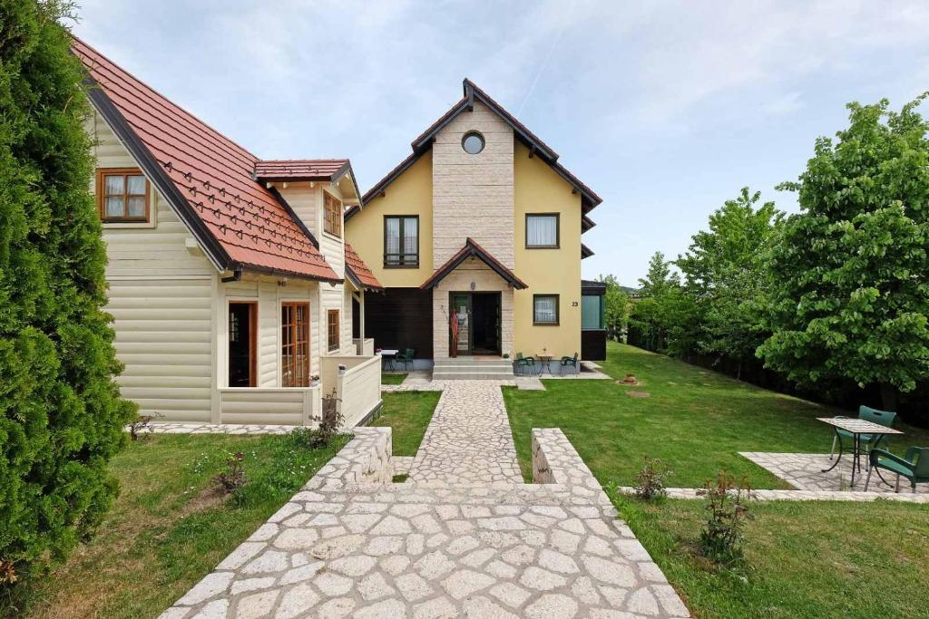 a yellow house with a pathway in front of it at Apartments Bohemia in Zlatibor