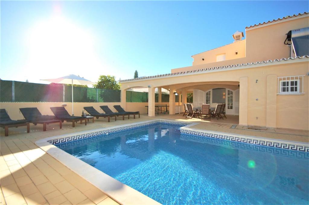 a swimming pool in front of a house at Qta do Eucalipto Villa in Faro