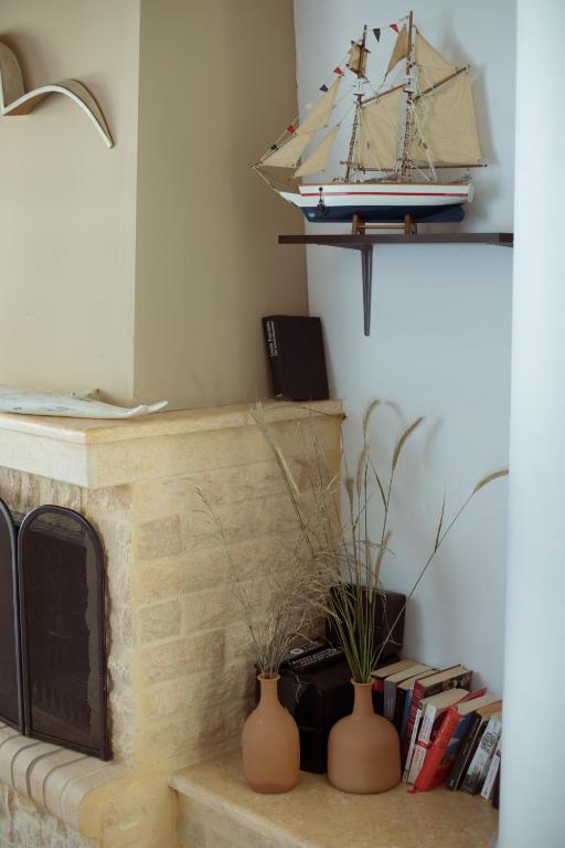 a fireplace with two vases and a model boat on a shelf at Sunset Home Crete in Paránimfoi