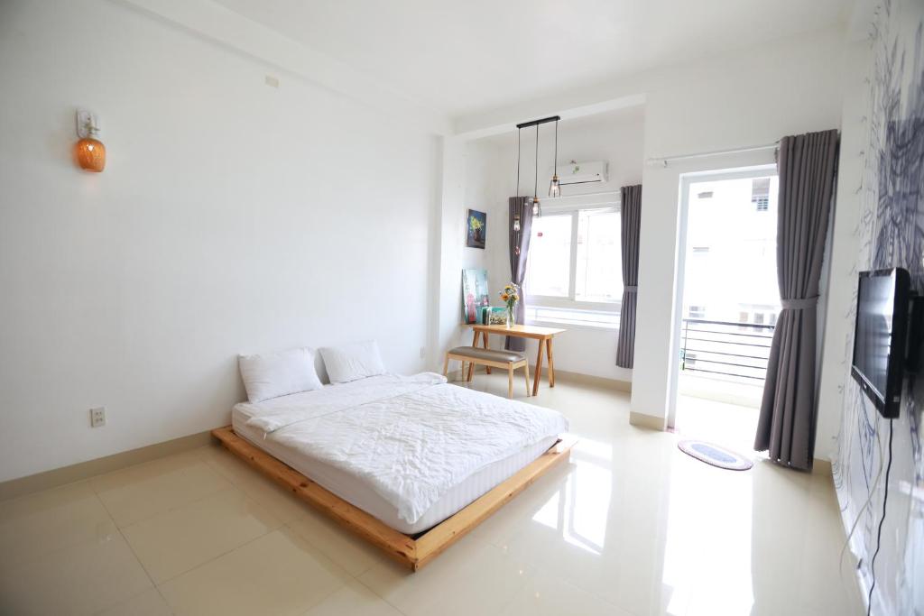 una camera bianca con letto e tavolo di Du Homestay 1 ad Ho Chi Minh