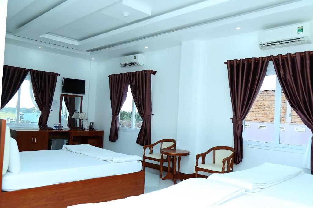 een slaapkamer met 2 bedden, een bureau en 2 stoelen bij HOTEL ĐĂNG KHOA 2 NÚI SAM in Chau Doc