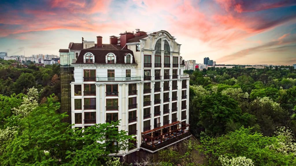 a tall white building in the middle of trees at Time Hotel&SPA in Chişinău