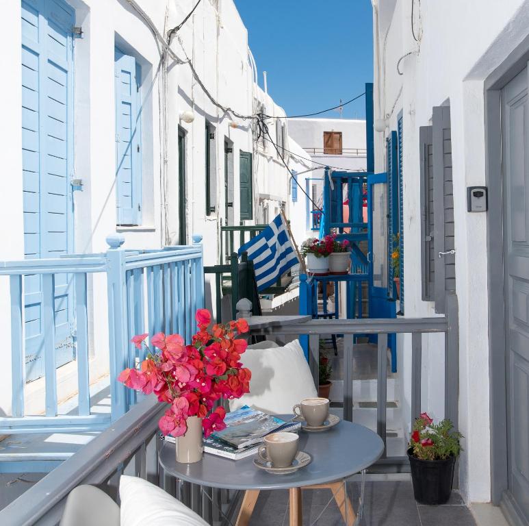 Un balcón con una mesa y flores. en Alessios Houses Mykonos Town en Mykonos