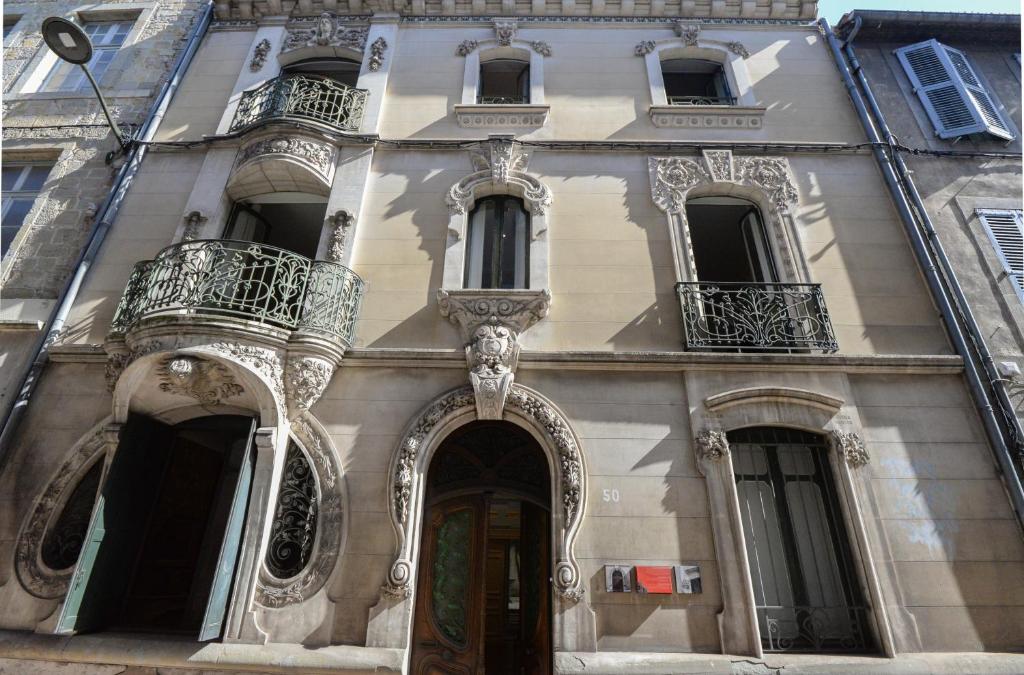 a building with balconies and a door on a street at La Maison de L' Ambassadeur Carcassonne in Carcassonne