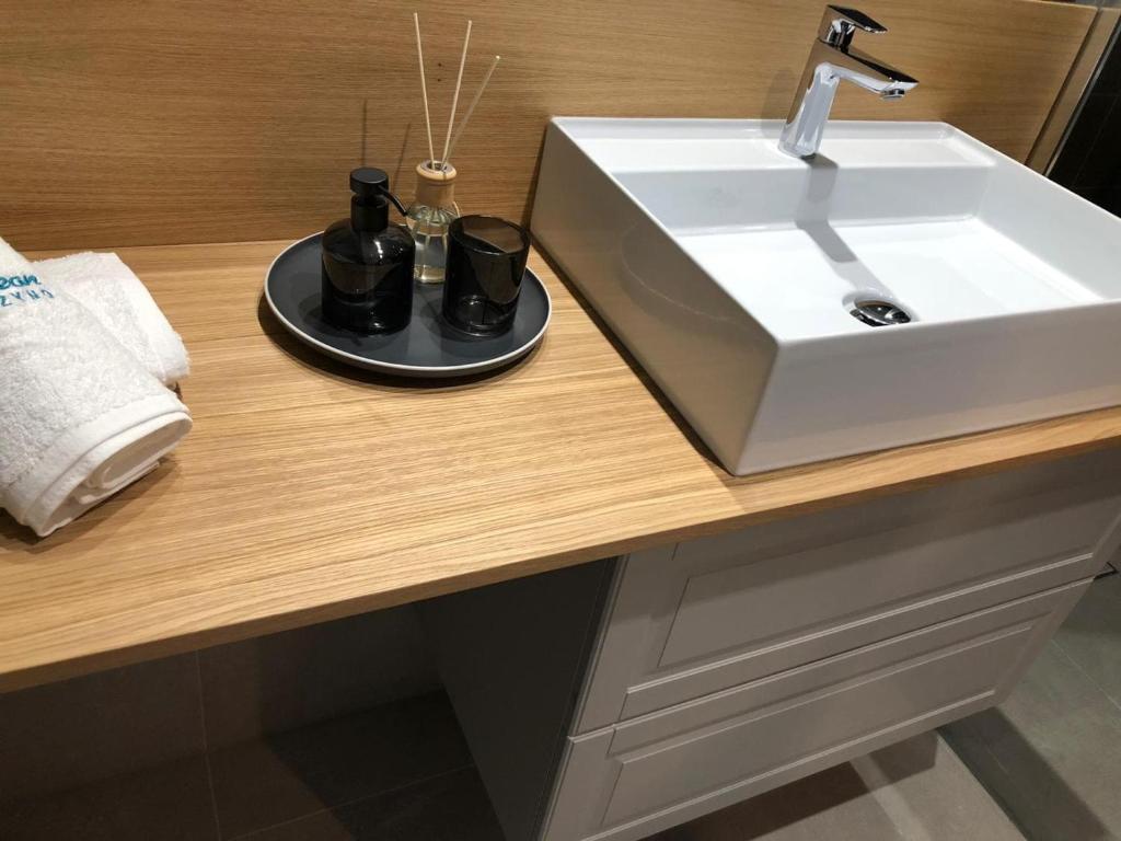 a bathroom counter with a sink and two cups at Apartament Kameleon in Dźwirzyno