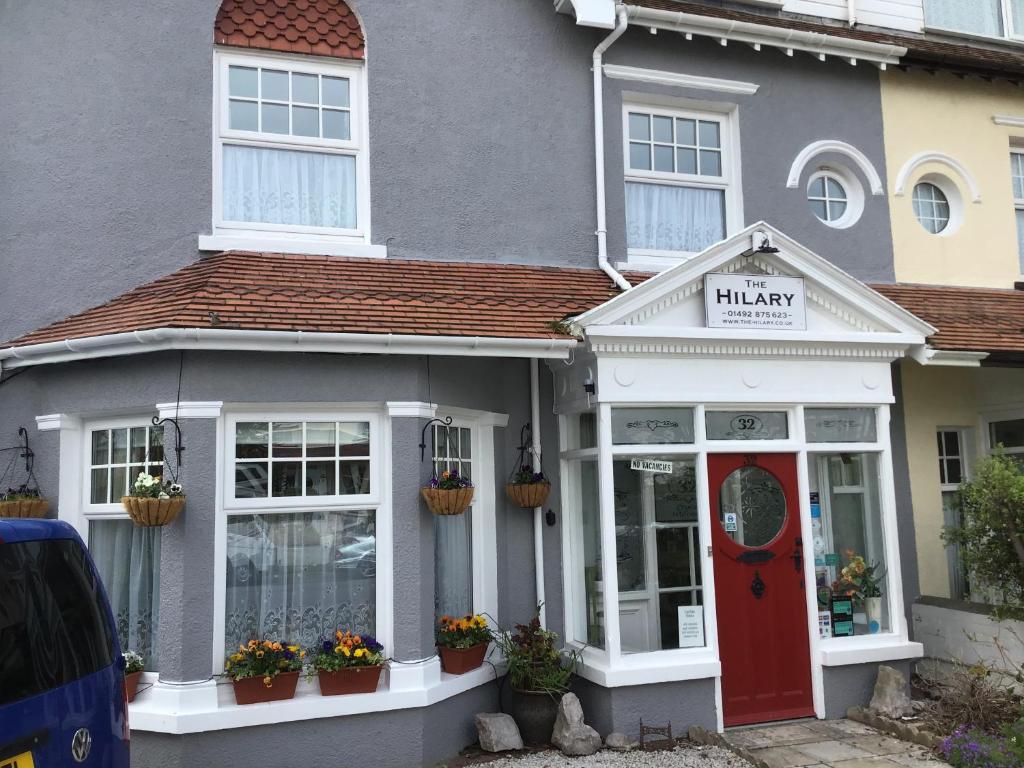 una casa con una farmacia con una puerta roja en The Hilary Guesthouse en Llandudno