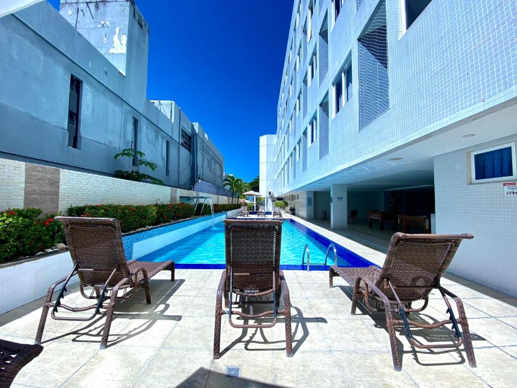 un grupo de sillas sentadas junto a una piscina en Nobile Suítes Tambaú en João Pessoa