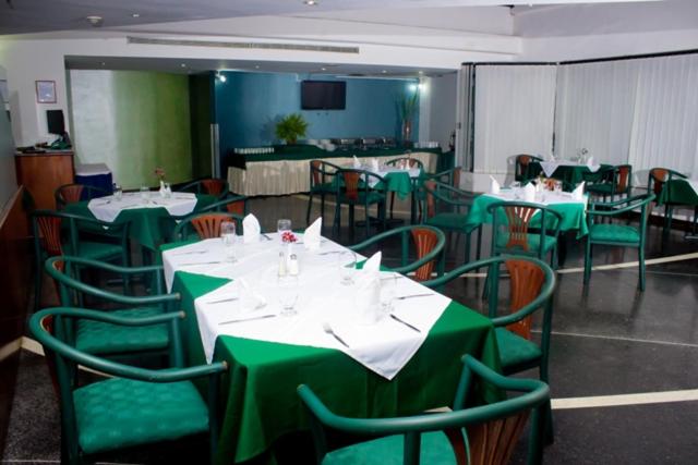 un comedor con mesas verdes y sillas en Hotel Chacao Cumberland, en Caracas