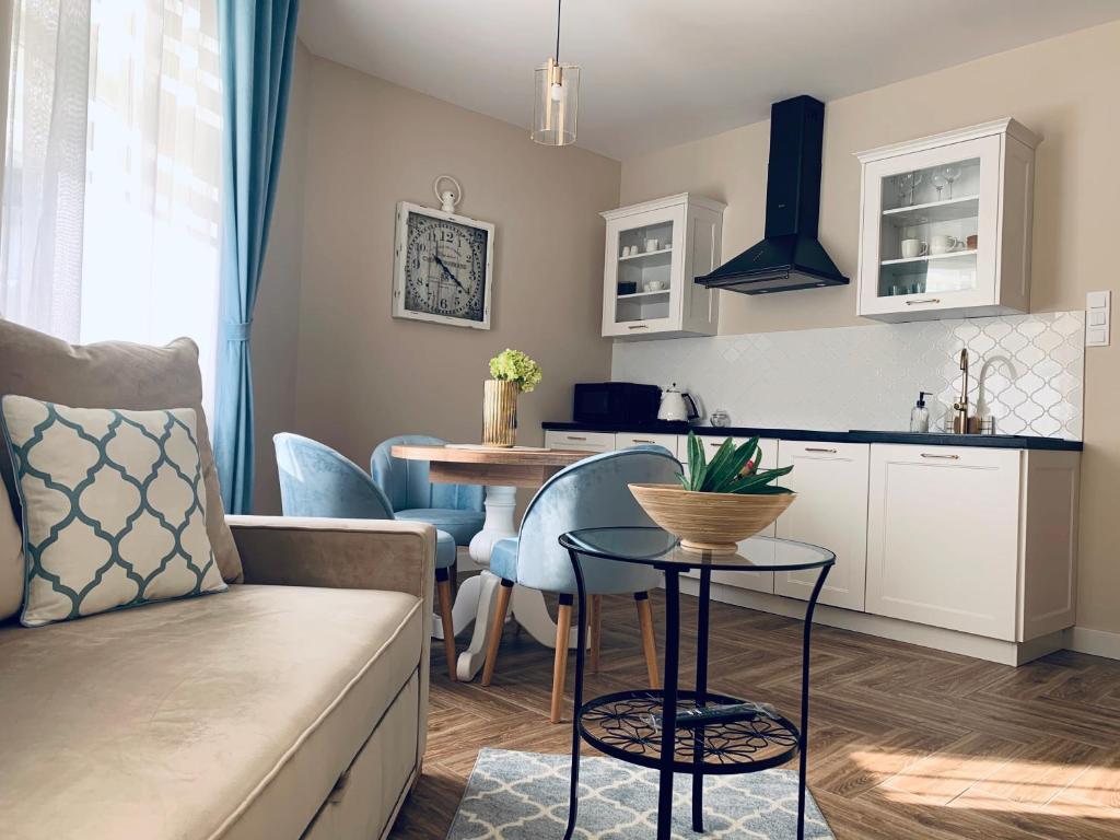 a kitchen and living room with a couch and a table at Apartamenty Kamienica Arte 1 in Ustka